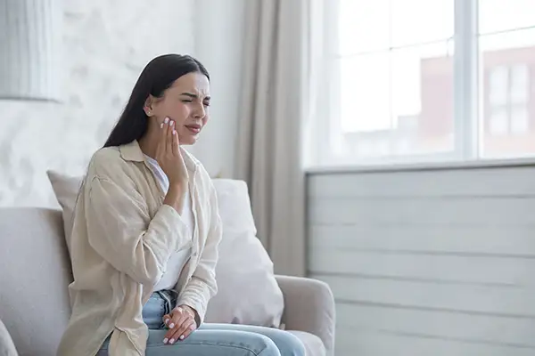 Woman holding her jaw experiencing dental emergency pain