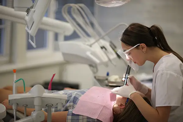 Dentist performing a restorative dental procedure on a patient in a modern dental clinic setting. Dentist performing a restorative dental procedure on a patient in a modern dental clinic setting.